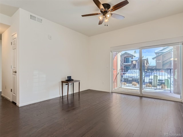 unfurnished room featuring baseboards, visible vents, a ceiling fan, dark wood-type flooring, and a city view