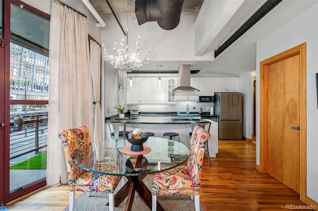 dining area with light wood finished floors, a towering ceiling, and a notable chandelier