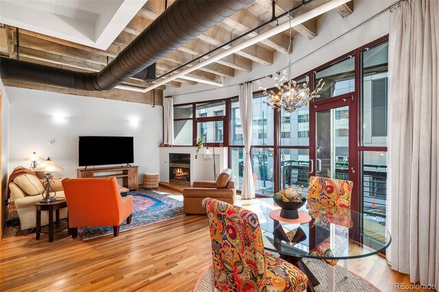 living room with beam ceiling, light hardwood / wood-style flooring, and a notable chandelier