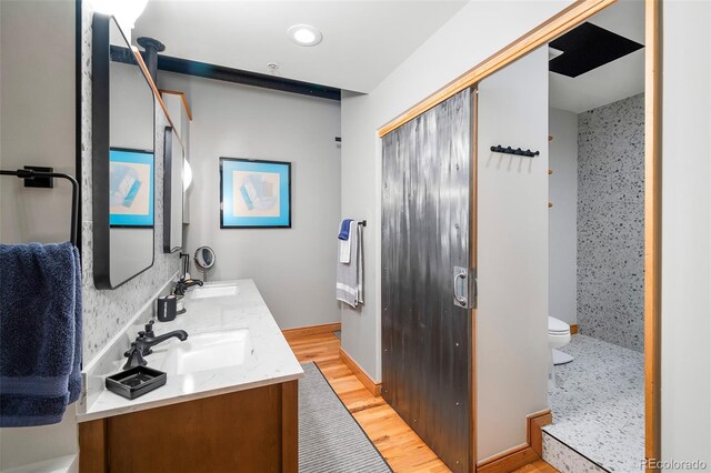 bathroom with walk in shower, dual bowl vanity, hardwood / wood-style flooring, and toilet