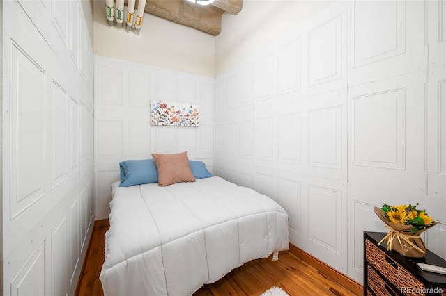 bedroom featuring a decorative wall and wood finished floors