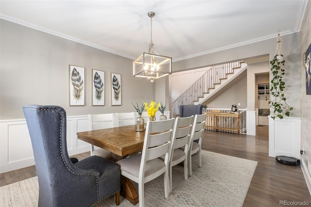 dining space featuring a wainscoted wall, ornamental molding, stairway, dark wood-style floors, and an inviting chandelier