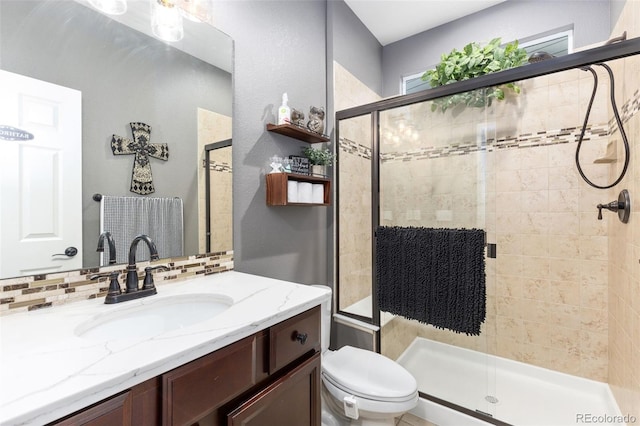 bathroom with toilet, a shower stall, tasteful backsplash, and vanity