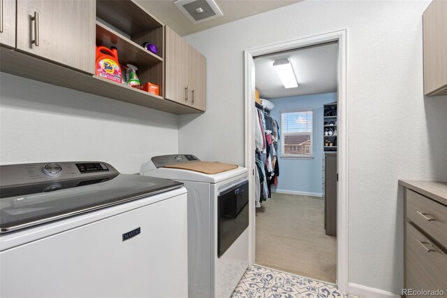 washroom with light carpet, visible vents, baseboards, cabinet space, and washer and clothes dryer