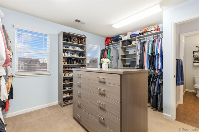 walk in closet with visible vents and light colored carpet