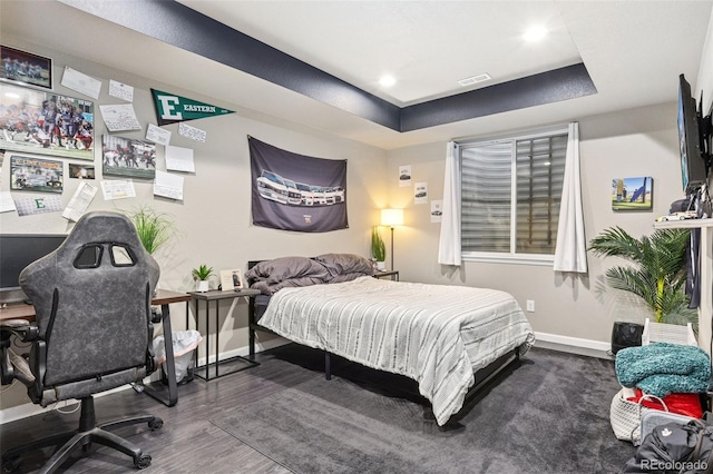 bedroom with recessed lighting, wood finished floors, visible vents, baseboards, and a tray ceiling