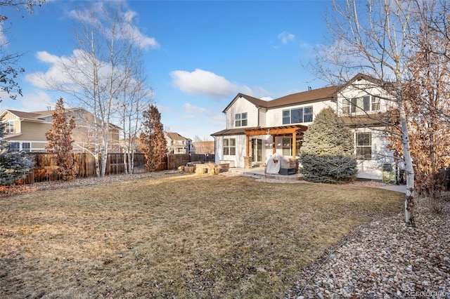 rear view of property featuring a yard, a patio area, and fence