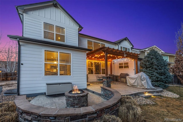 back of house featuring board and batten siding, an outdoor fire pit, a patio area, and a pergola