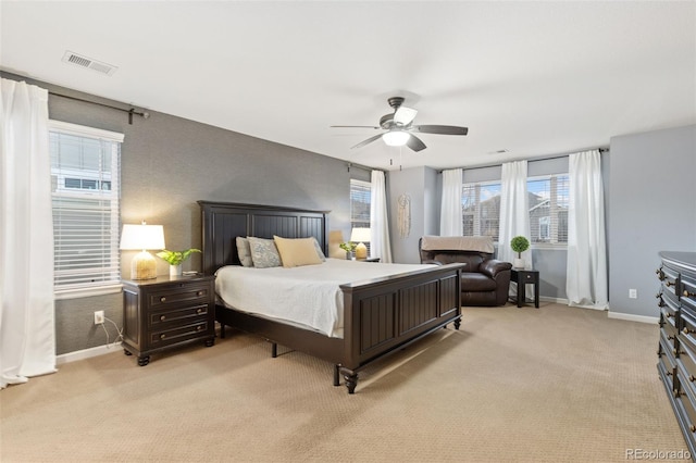 bedroom with light carpet, a ceiling fan, visible vents, and baseboards