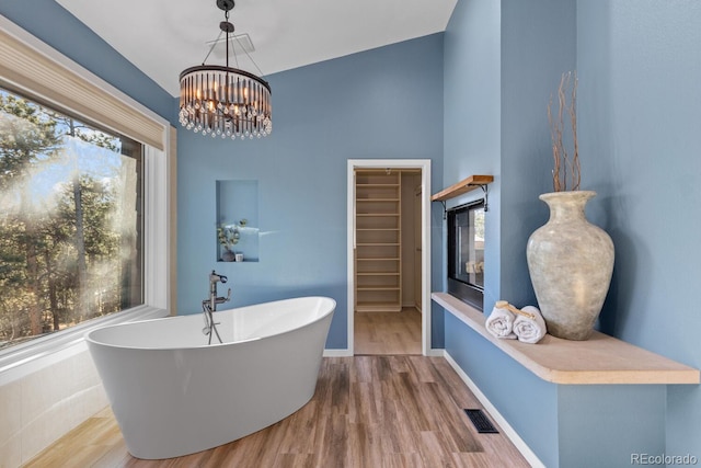 bathroom with an inviting chandelier, a washtub, hardwood / wood-style floors, and plenty of natural light