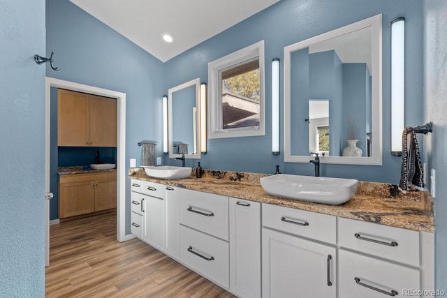 bathroom featuring hardwood / wood-style floors, lofted ceiling, and vanity