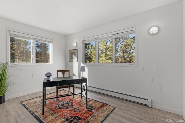 office space featuring light wood-type flooring, a baseboard radiator, and a wealth of natural light