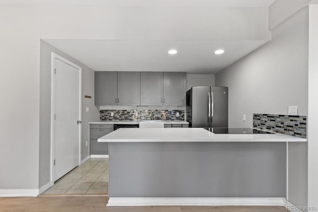 kitchen with black appliances, gray cabinetry, backsplash, and kitchen peninsula