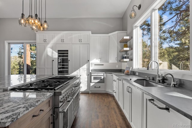 kitchen with stainless steel appliances, sink, white cabinets, dark stone counters, and plenty of natural light