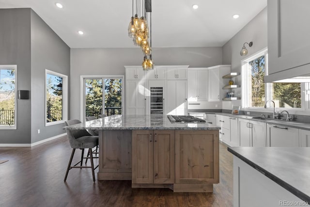 kitchen with sink, white cabinets, a center island, decorative light fixtures, and plenty of natural light