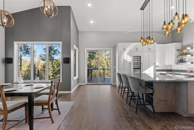 kitchen featuring hanging light fixtures, white cabinetry, dark stone countertops, and a towering ceiling