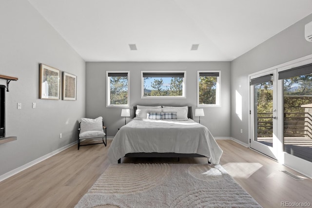 bedroom featuring vaulted ceiling, light wood-type flooring, access to outside, and a wall mounted AC