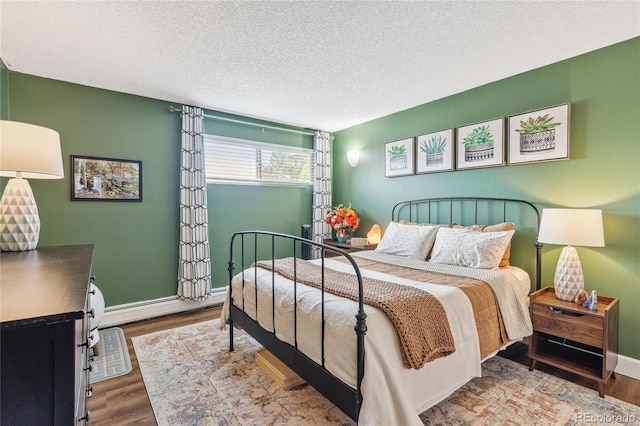 2835 S Monaco Pkwy Unit 1-103, Denver, CO 80222 - bedroom featuring a baseboard radiator, wood finished floors, and a textured ceiling