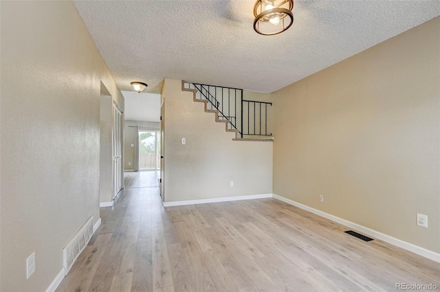 2726 Dickens Dr, Colorado Springs, CO 80916 - unfurnished living room with light wood-style floors, a textured ceiling, stairway, and baseboards