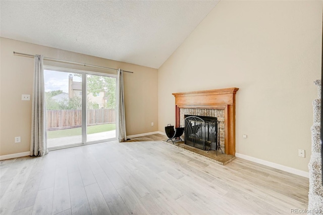 2726 Dickens Dr, Colorado Springs, CO 80916 - unfurnished living room with wood finished floors, a brick fireplace, baseboards, high vaulted ceiling, and a textured ceiling