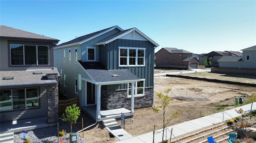 view of front of home with a porch, stone siding, and board and batten siding