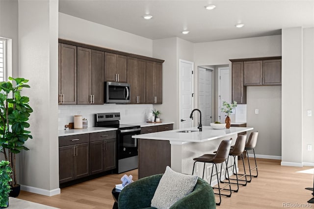 20871 E 60th Ave, Aurora, CO 80019 - kitchen featuring stainless steel appliances, a sink, decorative backsplash, light wood-style floors, and dark brown cabinetry