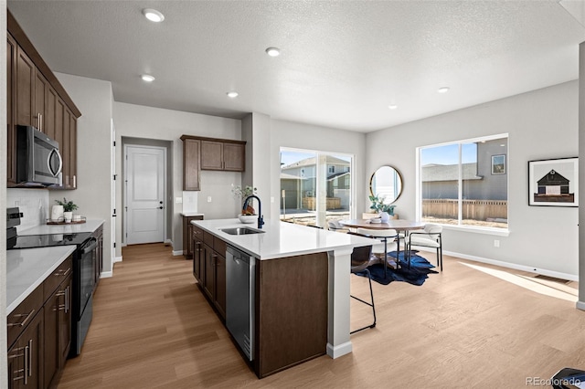 20871 E 60th Ave, Aurora, CO 80019 - kitchen featuring appliances with stainless steel finishes, a sink, light wood-style floors, baseboards, and a kitchen island with sink