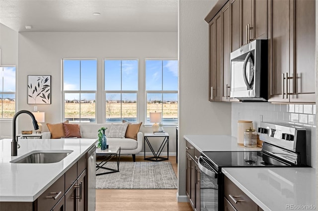 20871 E 60th Ave, Aurora, CO 80019 - kitchen with stainless steel appliances, a sink, open floor plan, light wood-style floors, and light countertops