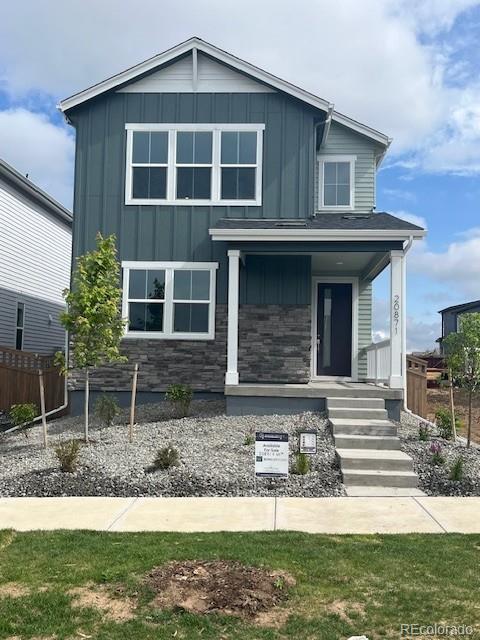 20871 E 60th Ave, Aurora, CO 80019 - view of front facade featuring board and batten siding, covered porch, and stone siding