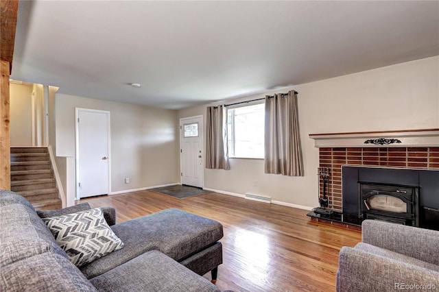 living area with baseboards, stairway, a tiled fireplace, and wood finished floors