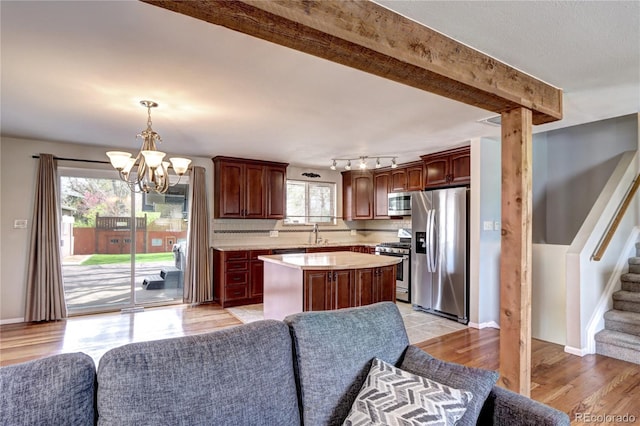 kitchen featuring a sink, a chandelier, light countertops, appliances with stainless steel finishes, and a kitchen island