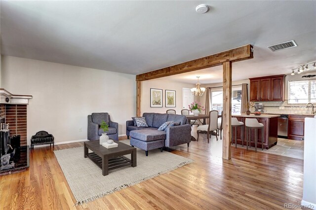 living room featuring light wood finished floors, a notable chandelier, and visible vents