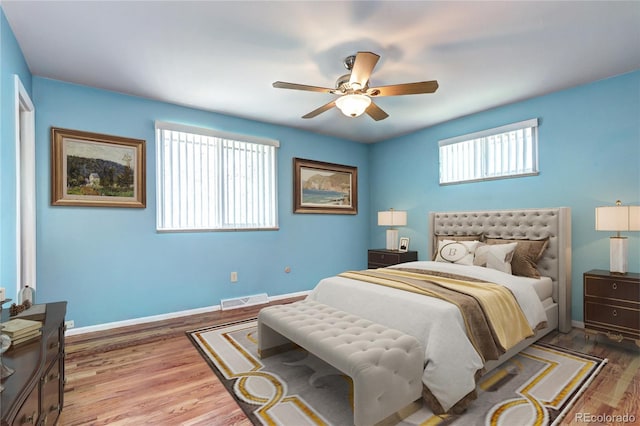 bedroom with baseboards, a ceiling fan, visible vents, and wood finished floors
