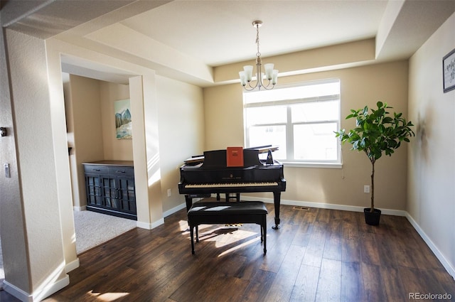 miscellaneous room with dark wood-type flooring, a tray ceiling, and a chandelier