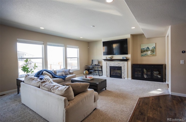 carpeted living area with a tiled fireplace, recessed lighting, baseboards, and a textured ceiling