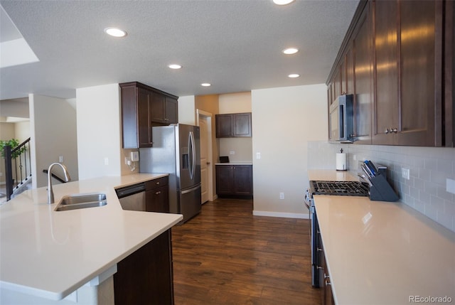 kitchen featuring a sink, light countertops, decorative backsplash, stainless steel appliances, and dark wood-style flooring