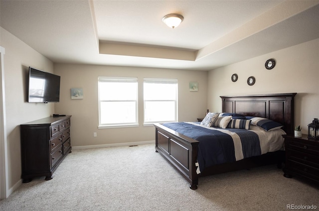 bedroom featuring baseboards, a raised ceiling, and light colored carpet