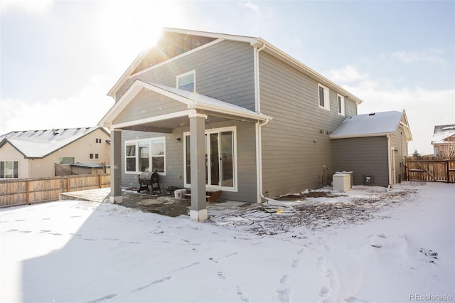 snow covered house featuring a patio and fence