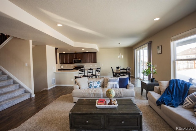 living room featuring visible vents, a chandelier, stairs, recessed lighting, and dark wood-style floors