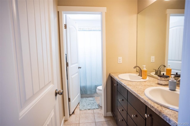 bathroom featuring double vanity, toilet, tile patterned floors, and a sink