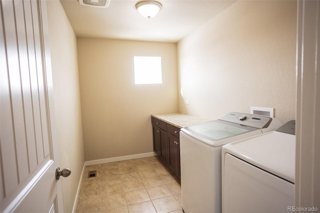 washroom featuring light tile patterned flooring, cabinet space, baseboards, and washer and clothes dryer