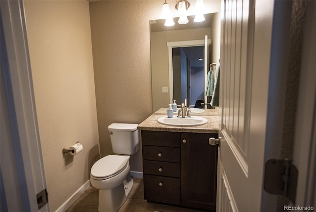 bathroom with baseboards, toilet, a textured wall, tile patterned floors, and vanity