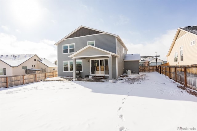 snow covered house featuring a fenced backyard