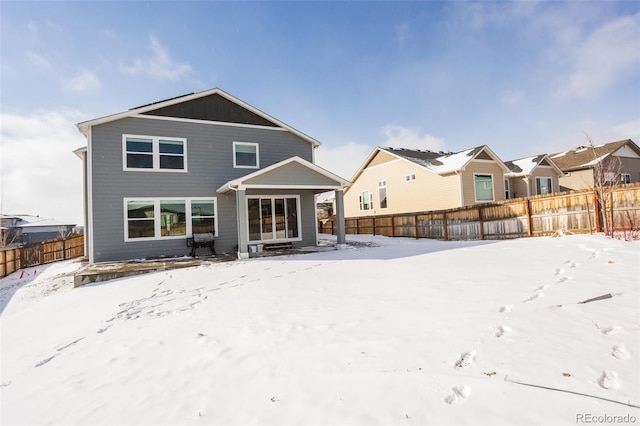 snow covered rear of property featuring a residential view and fence private yard