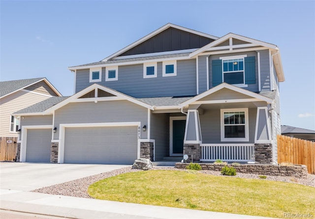 8073 Wheatland Dr, Colorado Springs, CO 80908 - craftsman inspired home featuring a front lawn, an attached garage, fence, stone siding, and a porch