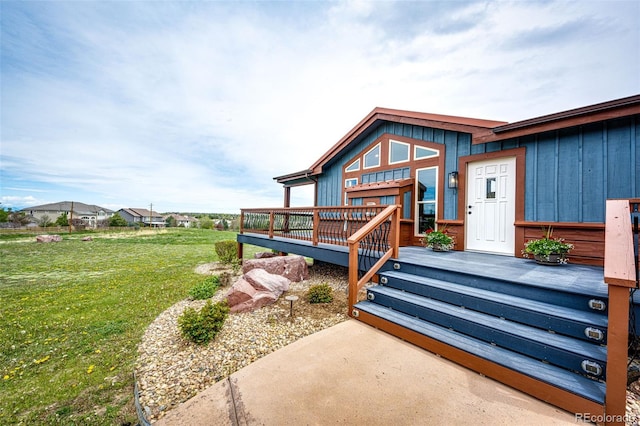doorway to property featuring a deck, a lawn, and board and batten siding