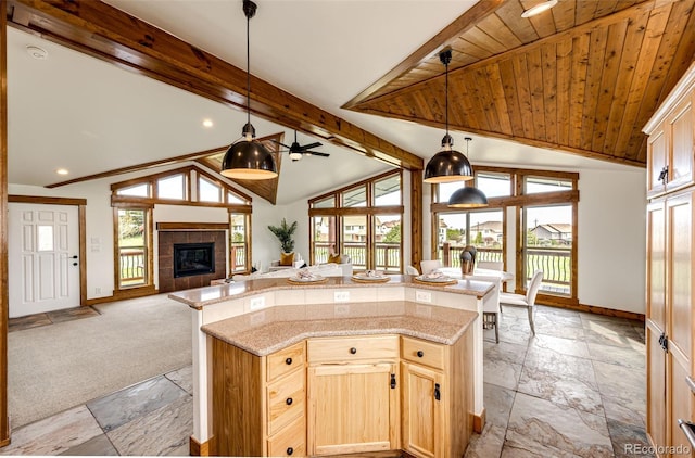 kitchen featuring stone tile floors, baseboards, open floor plan, plenty of natural light, and beam ceiling