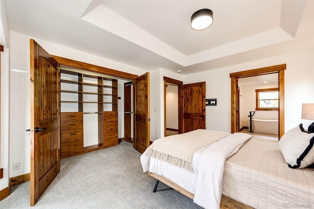 bedroom featuring a raised ceiling, light colored carpet, and baseboards