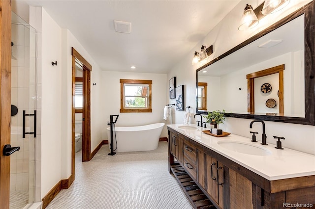 full bathroom with baseboards, a shower stall, a freestanding tub, toilet, and double vanity