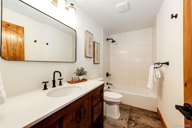 bathroom featuring toilet, vanity, bathtub / shower combination, stone finish flooring, and baseboards